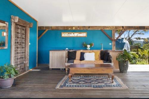 a living room with a couch and a blue wall at Golden Domes in Cootharaba