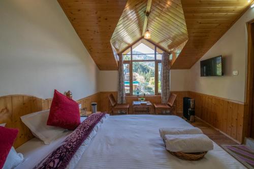 a large bed in a room with a large window at Urban Monk Stays and Cafe in Manāli