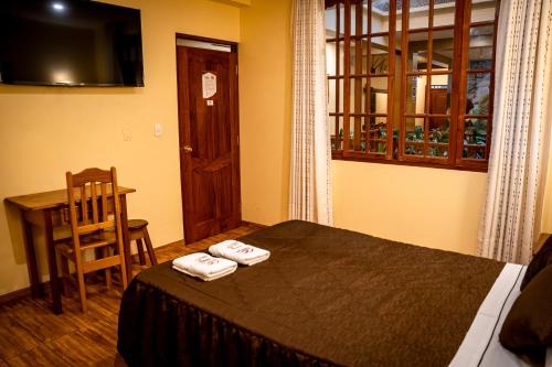 a bedroom with a bed and a table and a window at Hospedaje Chimy in Oxapampa