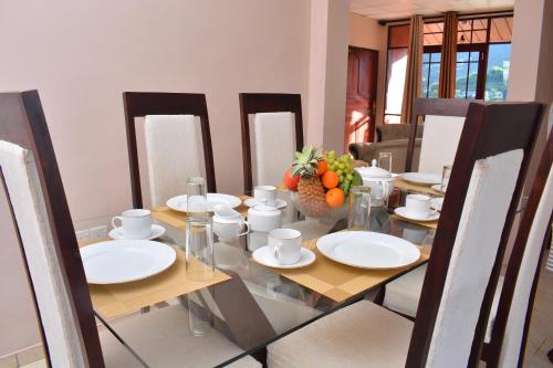 a dining room table with white plates and oranges on it at Royal Apartments in Nuwara Eliya