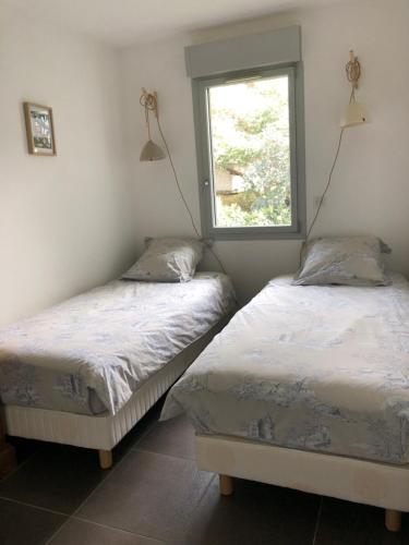 deux lits jumeaux dans une chambre avec fenêtre dans l'établissement Appartement T3 à 2mn de la Plage, à LʼÎle-Rousse
