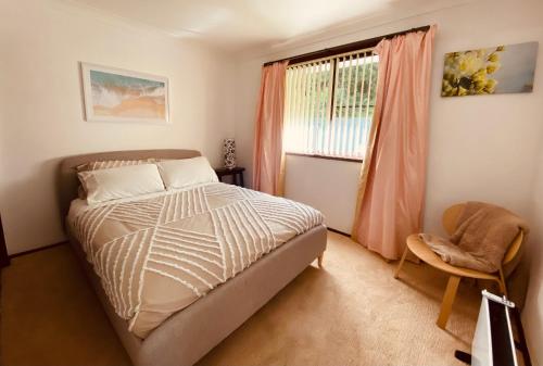 a bedroom with a bed and a window and a chair at Relaxing at acreage farmhouse in Burrawang