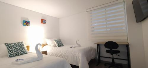 Un dormitorio con dos camas con cisnes. en Amplio apartamento lujoso al lado del lago, en Paipa