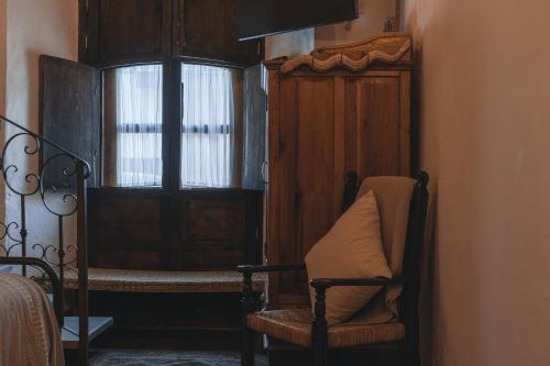a room with a bed and a chair and a window at El Edén Hotel Boutique in Pátzcuaro