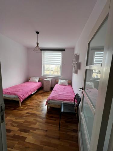 Duas camas num quarto com lençóis cor-de-rosa e pisos em madeira em Do Gdyni Exclusive em Gdynia
