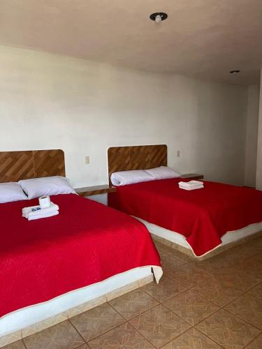 two beds with red covers in a room at REBOLLEDO IMPERIAL cerca de grutas tolantongo in San Cristóbal