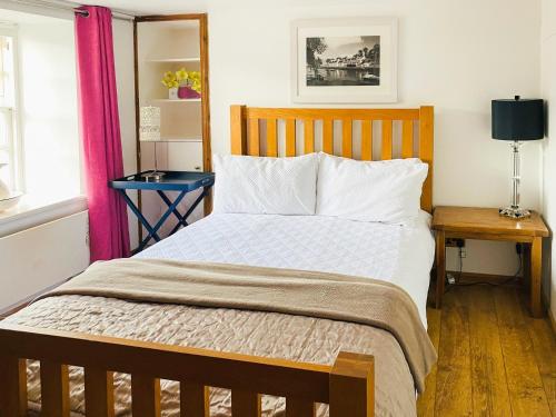 a bedroom with a large bed with a wooden headboard at Cobble Cottage in Cramond