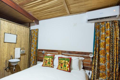 a bedroom with a bed and a tv on the wall at Nxabii Cottages in Kasane