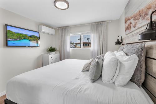 a white bedroom with a large white bed with pillows at Tower 9 #4 in Oceanside