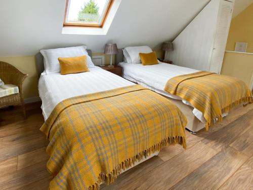 duas camas com cobertores amarelos num quarto em A Twist Of Lyme em Blackpool Corner