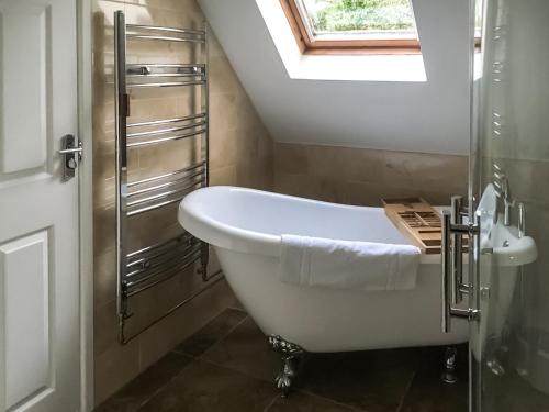 uma banheira branca na casa de banho com uma janela em A Twist Of Lyme em Blackpool Corner