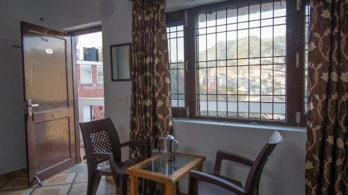 a dining room with a table and chairs and a window at Irish Town Mussoorie in Mussoorie