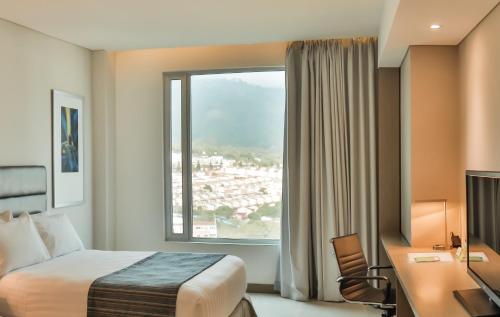 a hotel room with a bed and a desk and a window at Holiday Inn Bucaramanga Cacique by IHG in Bucaramanga