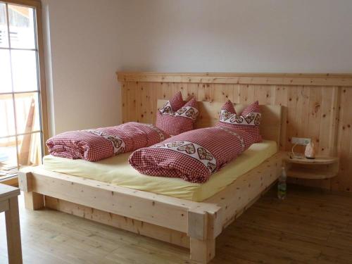 a bedroom with a wooden bed with pillows on it at Holzberghof in Umhausen