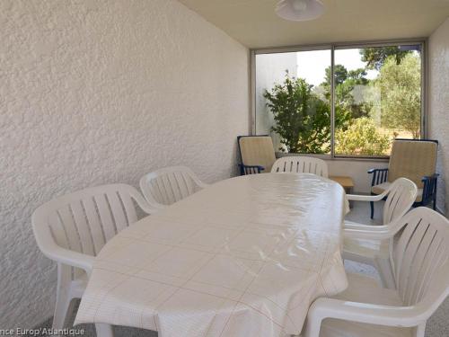 une table blanche et des chaises dans une pièce avec une fenêtre dans l'établissement Belle Villa 4 Pièces à 150m de la Mer, 6 Pers, Patio, BBQ, Parking - LA PALMYRE - FR-1-705-11, à La Palmyre