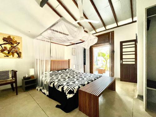 a bedroom with a bed and a bench in it at Isana Beach House in Tangalle