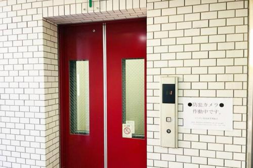 a red door in a white brick building at マリオン屋島東906号 in Sanuki