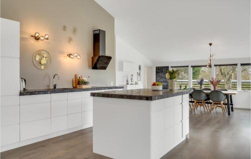 an open kitchen with white cabinets and a dining room at Luxurious Home In Ølsted in Ølsted