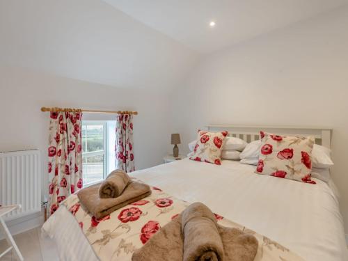 a bedroom with a large white bed with red roses at Gelli Villa in Llanglydwen