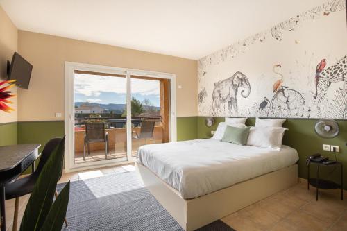 a bedroom with a bed and a table and a balcony at Hôtel La Perna in Pernes-les-Fontaines