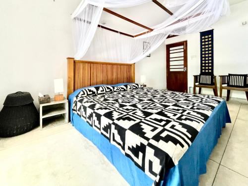 a bedroom with a bed with a black and white comforter at Isana Beach House in Tangalle