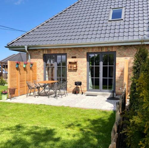 un patio con mesa y sillas frente a una casa en Landhaus 1884 OFC 17, en Beiershagen