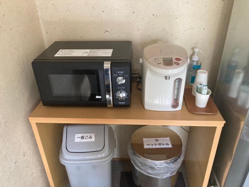 a microwave sitting on a table with a trash can at Oyado Raku in Takayama