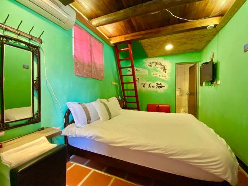 ein Schlafzimmer mit einer grünen Wand mit einem Bett und einer Leiter in der Unterkunft 彼岸古厝民宿-包棟優先--Biiann B&B in Jinning