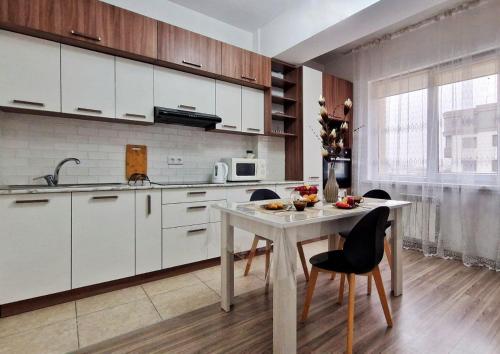 una cucina con mobili bianchi, tavolo e sedie di Высота полета a Almaty