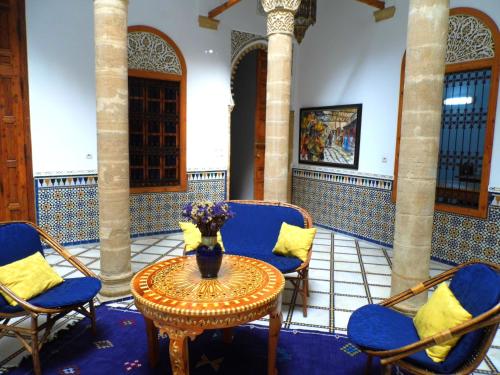 una habitación con sillas y una mesa con un jarrón. en Riad Marco Andaluz, en Sale