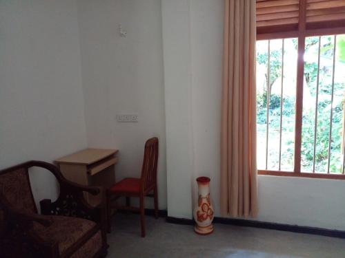 a room with a chair and a desk and a window at Villa Ameliya in Unawatuna