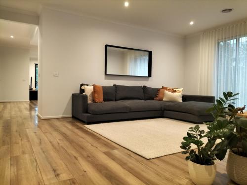 a living room with a couch and a mirror at Harvey's Haven in Castlemaine
