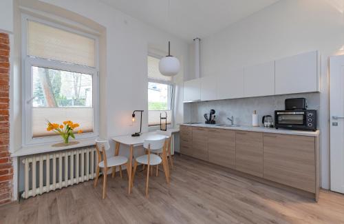 a kitchen with white cabinets and a table and chairs at Freedom Avenue Apartment by Polo apartments in Kaunas