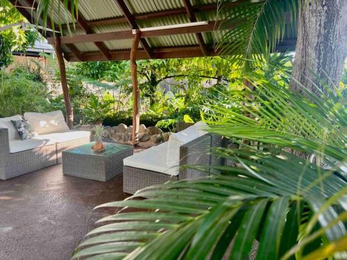 a patio with couches and a table and trees at Heitiare lodge in Paea