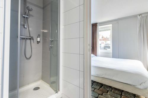 a white bathroom with a shower and a bed at Dav'hotel Jaude in Clermont-Ferrand