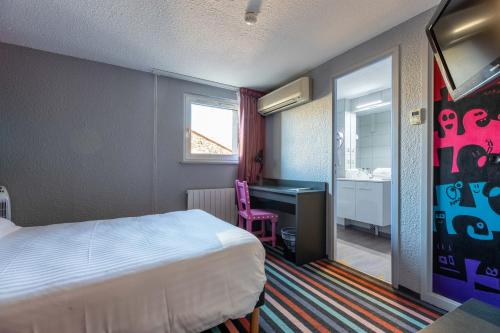 クレルモン・フェランにあるDav'hotel Jaudeのベッドとデスクが備わるホテルルームです。