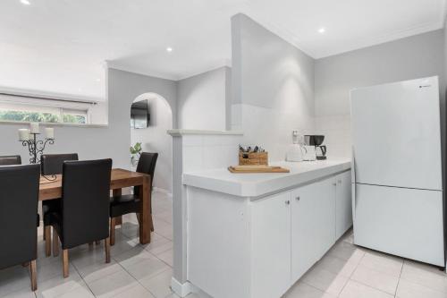 a kitchen and dining room with white cabinets and a table at Blackwood Stays in Spearwood