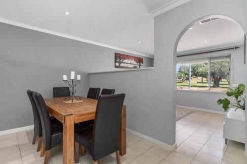 a dining room with a wooden table and black chairs at Blackwood Stays in Spearwood