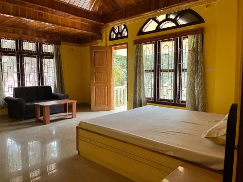 a bedroom with a bed and a chair and windows at Hilltop Homestay in Itānagar
