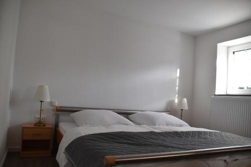 een slaapkamer met een bed met witte lakens en een raam bij Ferienwohnung-Naurath in Naurath