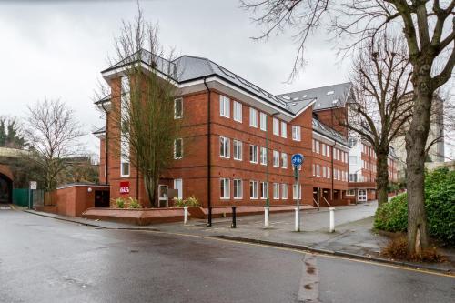 a large red brick building on the side of a street at Roomspace Serviced Apartments - Nouvelle House in Sutton