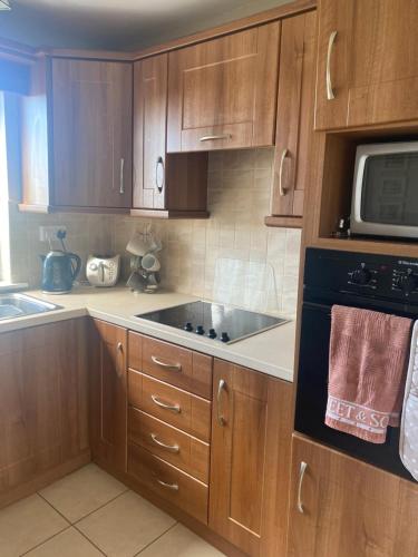 a kitchen with wooden cabinets and a sink and a microwave at Cruit Island Holiday Rent in Cruit