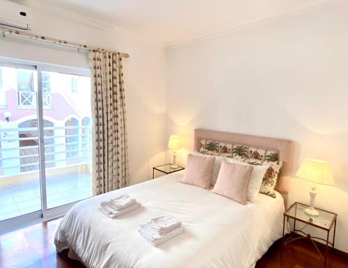um quarto com uma grande cama branca e uma janela em Vilamoura Central 2 Bedroom Apartment em Vilamoura