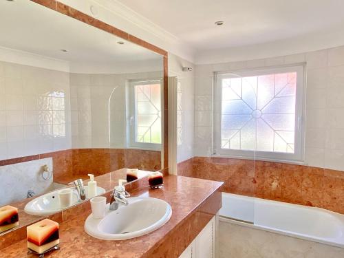 ein Badezimmer mit zwei Waschbecken, einer Badewanne und einem Spiegel in der Unterkunft Vilamoura Central 2 Bedroom Apartment in Vilamoura