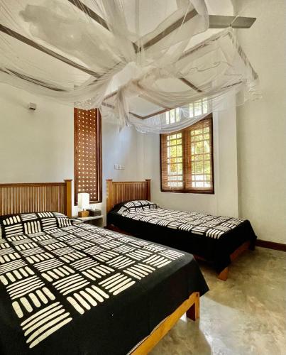 a bedroom with two beds and a ceiling at Isana Beach House in Tangalle