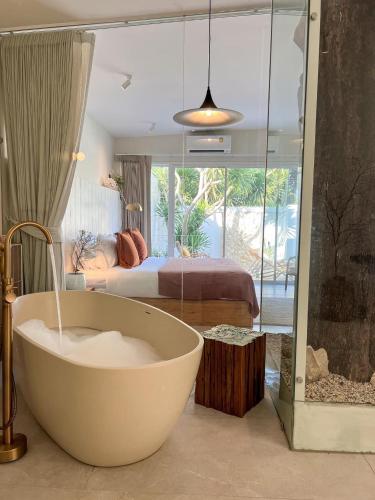 a bathroom with a bath tub and a bedroom at wyn in Ko Larn