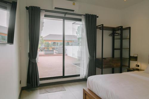 a bedroom with a bed and a sliding glass door at ONE LODGE Pattaya in Pattaya Central