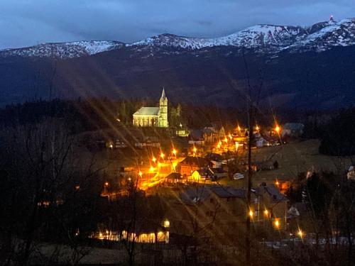 una ciudad iluminada por la noche con montañas cubiertas de nieve en Green Park Resort - Widokowy D14 z dostępem do Basenu, Sauny i Jacuzzi en Szklarska Poręba