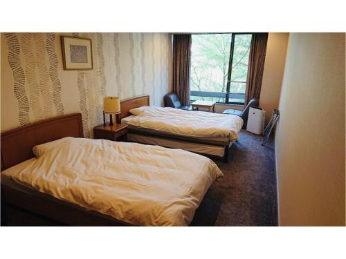 um quarto de hotel com duas camas e uma janela em Hotel Park em Gifu