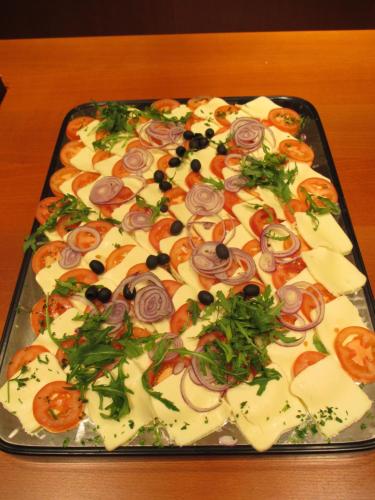 a pizza with tomatoes and cheese on a tray at Hotel Untermetzger in Zell am Ziller
